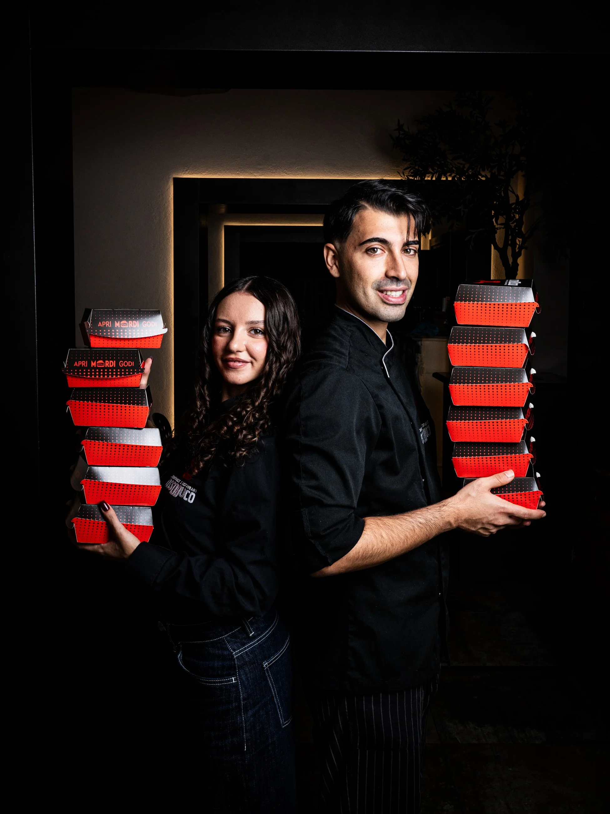 Emanuele e Francesca, fondatori di Ossobuco, con le pile di confezioni rosse da asporto